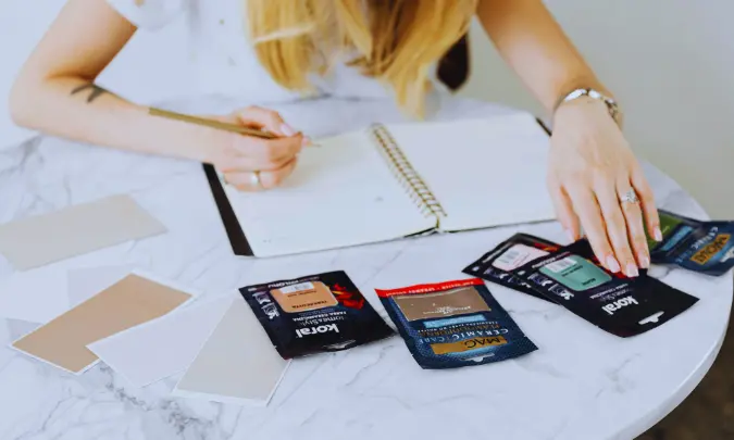 A writer reviewing color swatches and taking notes in a notebook while planning writing samples for a freelance portfolio.