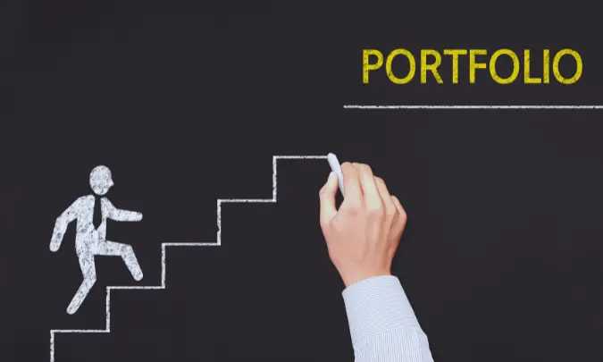 A hand drawing steps on a chalkboard labeled “Portfolio,” symbolizing the process of building a professional writing portfolio.