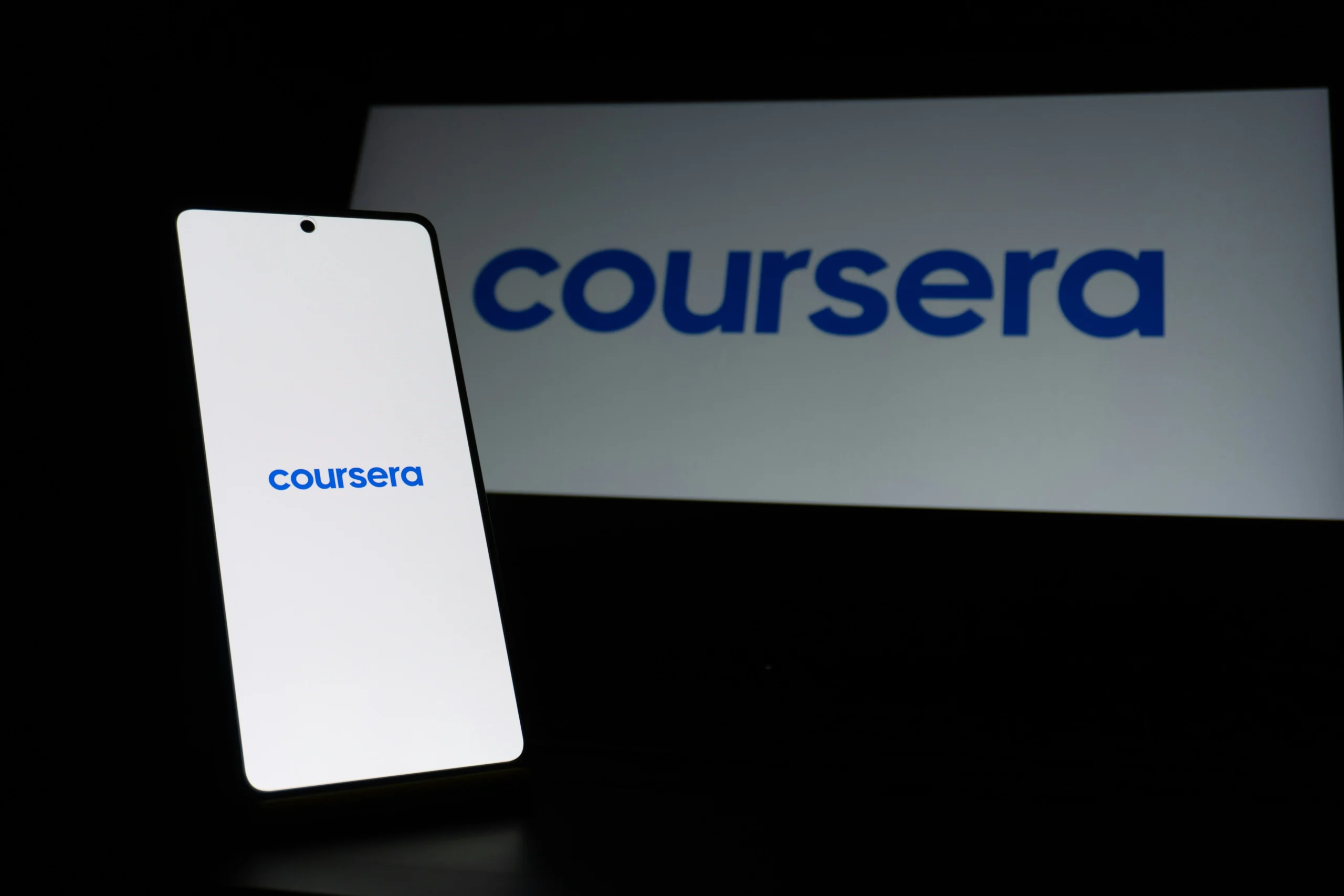 Coursera logo displayed on a smartphone and TV screen, illustrating Coursera's online learning platform and its mobile accessibility for structured academic courses, certificates, and degree programs in 2026.