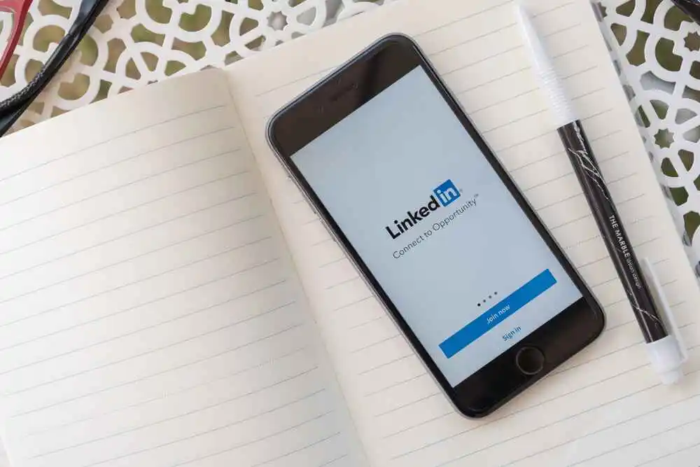 Smartphone displaying LinkedIn login screen on notebook desk, representing LinkedIn outreach strategy for virtual assistants